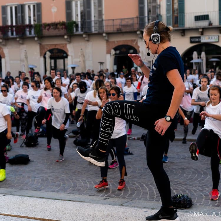 Istruttore guida una lezione di ballo in piazza con cuffie wireless